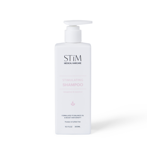 Stïm Haircare stimulating shampoo bottle with label, white and green packaging, on a neutral background.