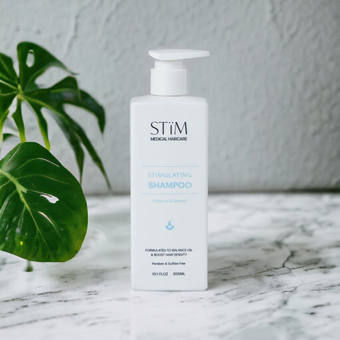 Stïm Haircare stimulating shampoo bottle with pump dispenser, featuring sleek design and label, on a white background