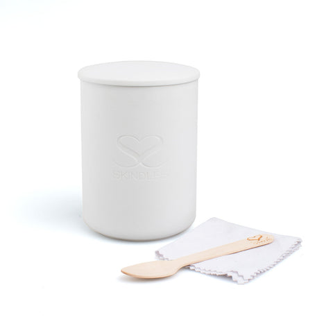 Skindles Frankincense Amber & Myrrh scented candle in a glass vessel with cloth and spoon, showcasing warm, earthy tones.